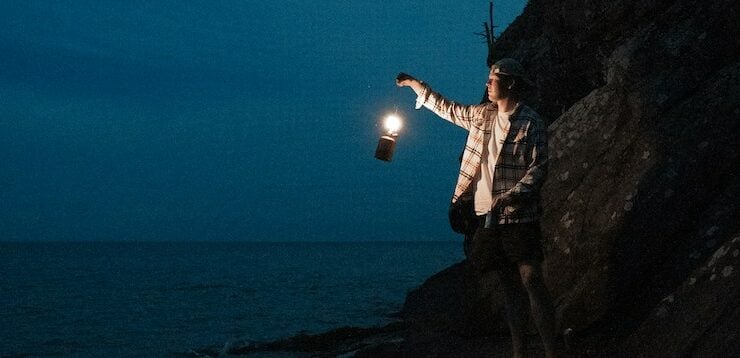 Man holding a lantern illuminating the shore of Lake Superior